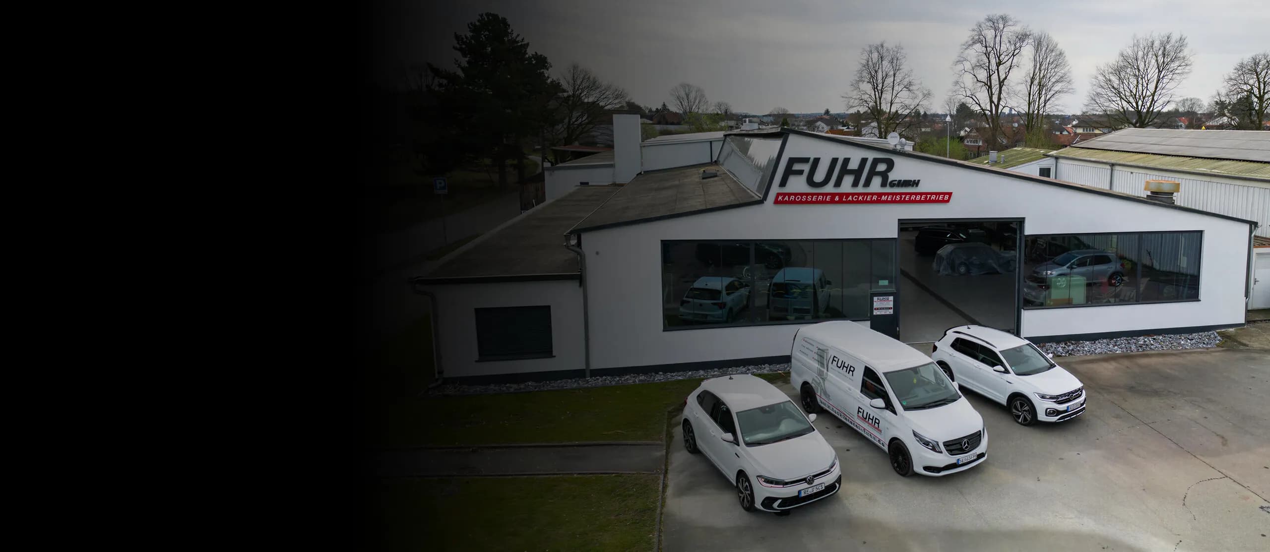 Gebäude der Fuhr GmbH Karosserie & Lackier-Meisterbetrieb mit weißen Firmenfahrzeugen davor.