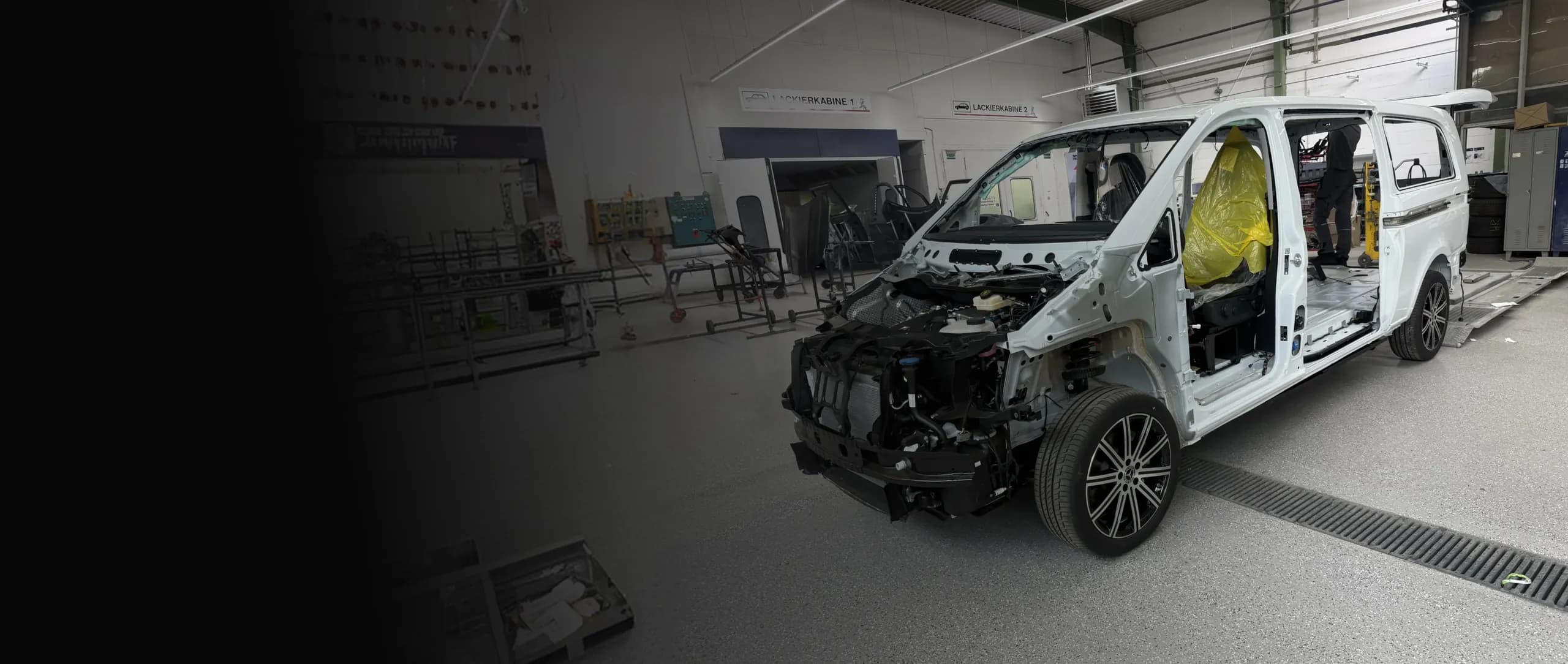 Ein weißer Transporter ohne Frontverkleidung steht zur Montage in einer hellen Werkstatthalle.
