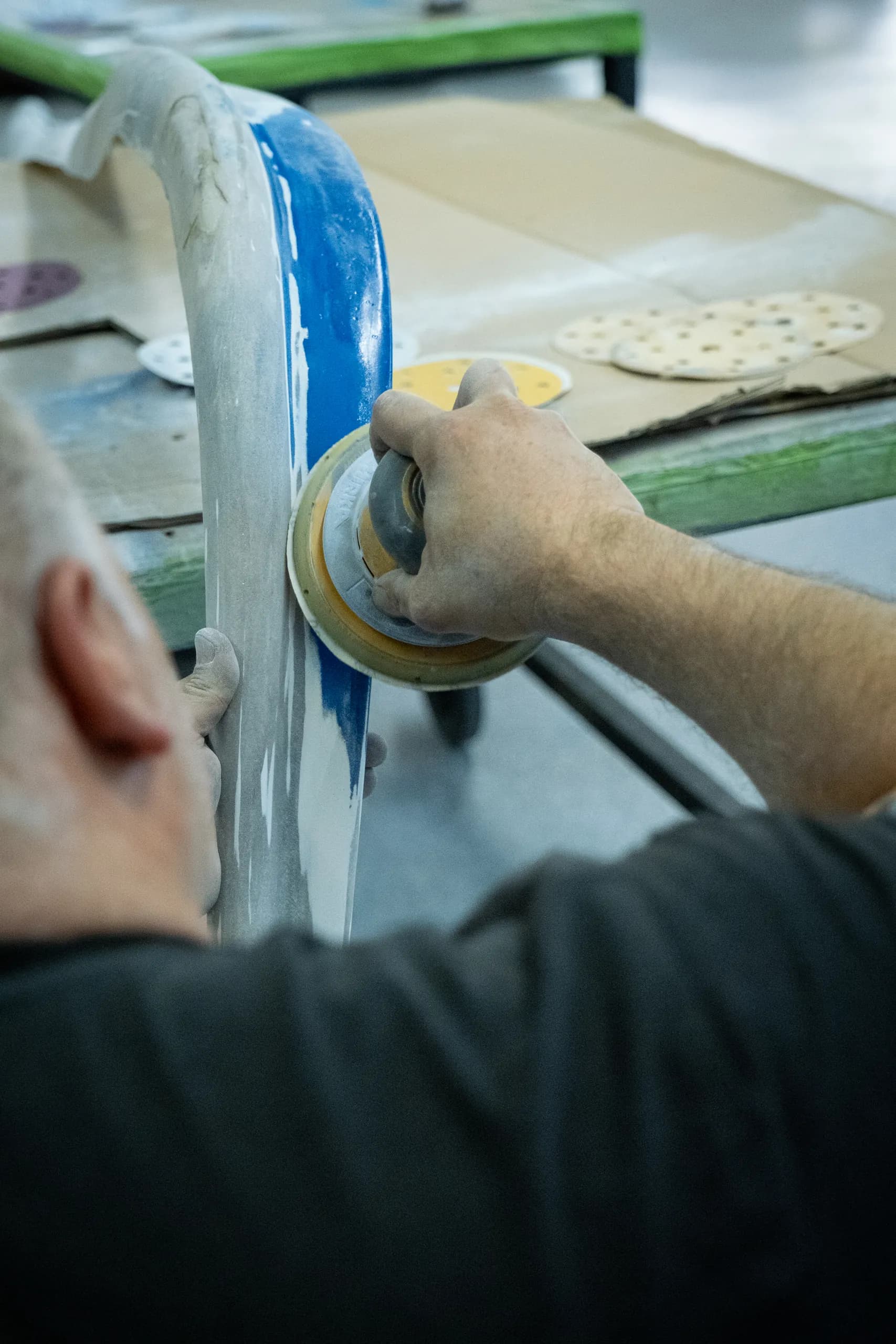Ein Handwerker bearbeitet ein Kunststoffbauteil mit einer Schleifmaschine.