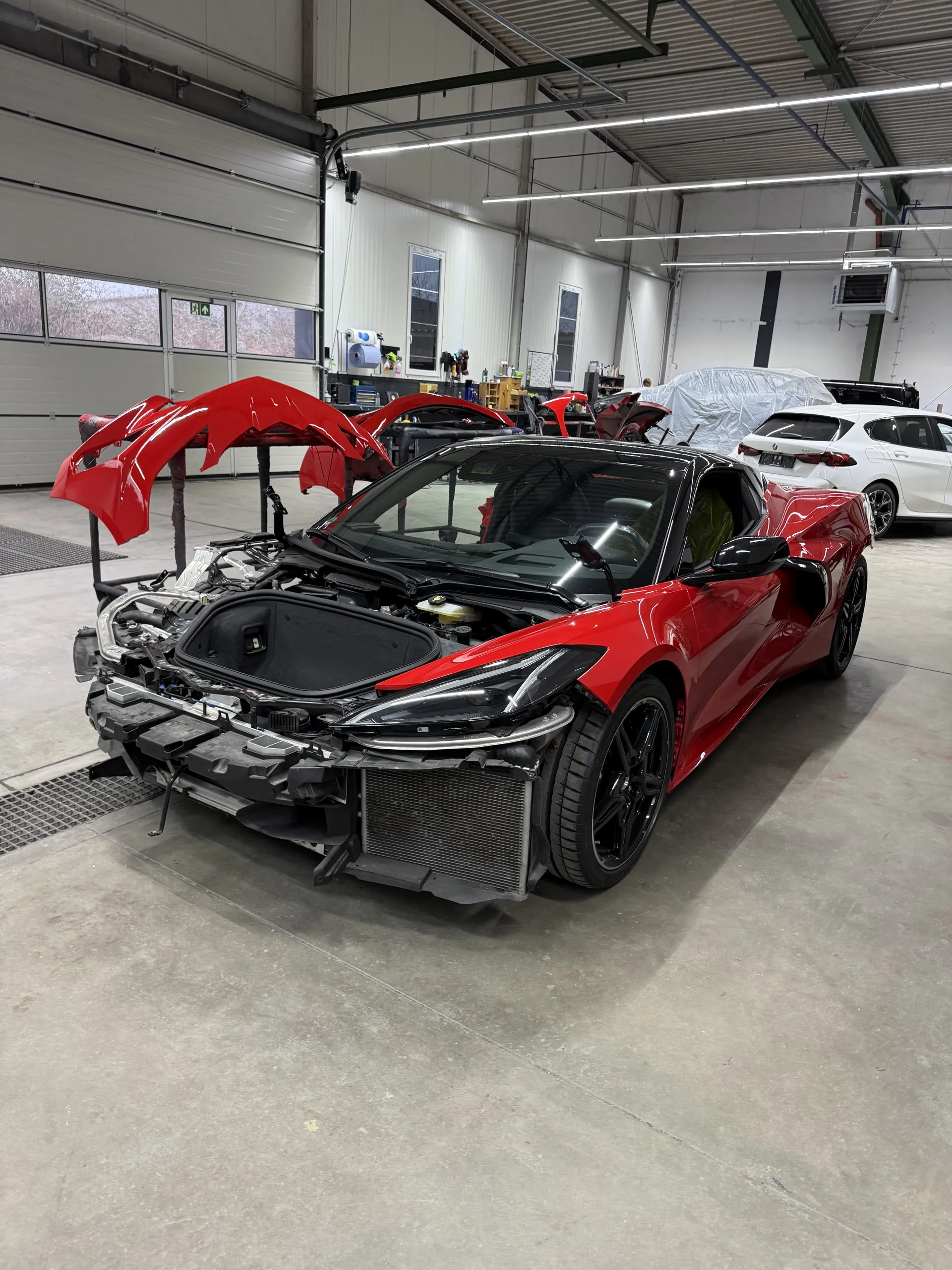 Roter Sportwagen mit demontierten Anbauteilen bei der Vorbereitung in der Werkstatt.