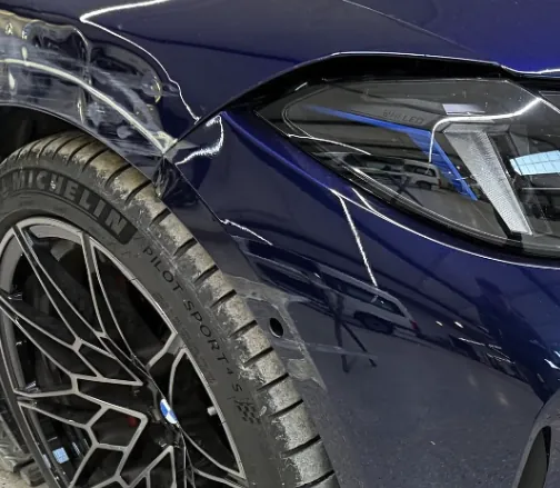 Kratzer am blauen Kotflügel eines Fahrzeugs vor dem Smart Repair.