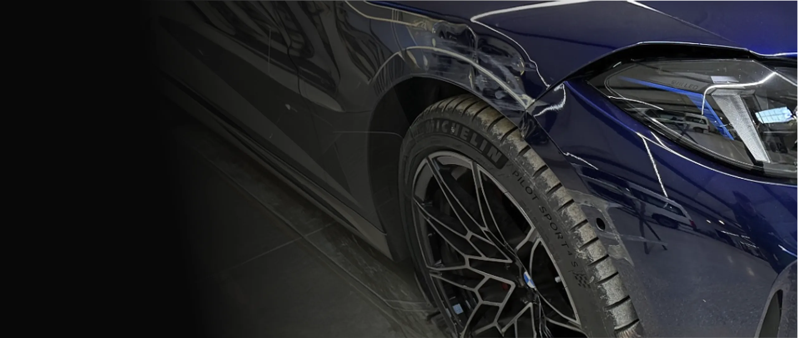 Nahaufnahme eines blauen Sportwagens mit Michelin-Reifen, schwarzen Alufelgen und LED-Scheinwerfer.